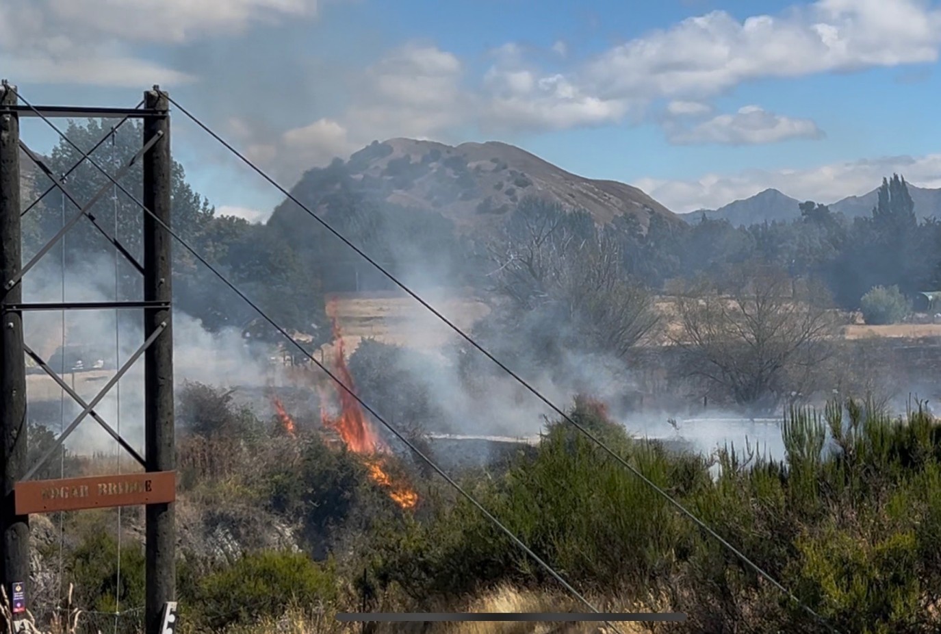 Fire rages through dry vegetation alongside the Gibbston Trail at Morven Ferry coming dangerously close to the Edgar Bridge. Photo Natalie Urbani
