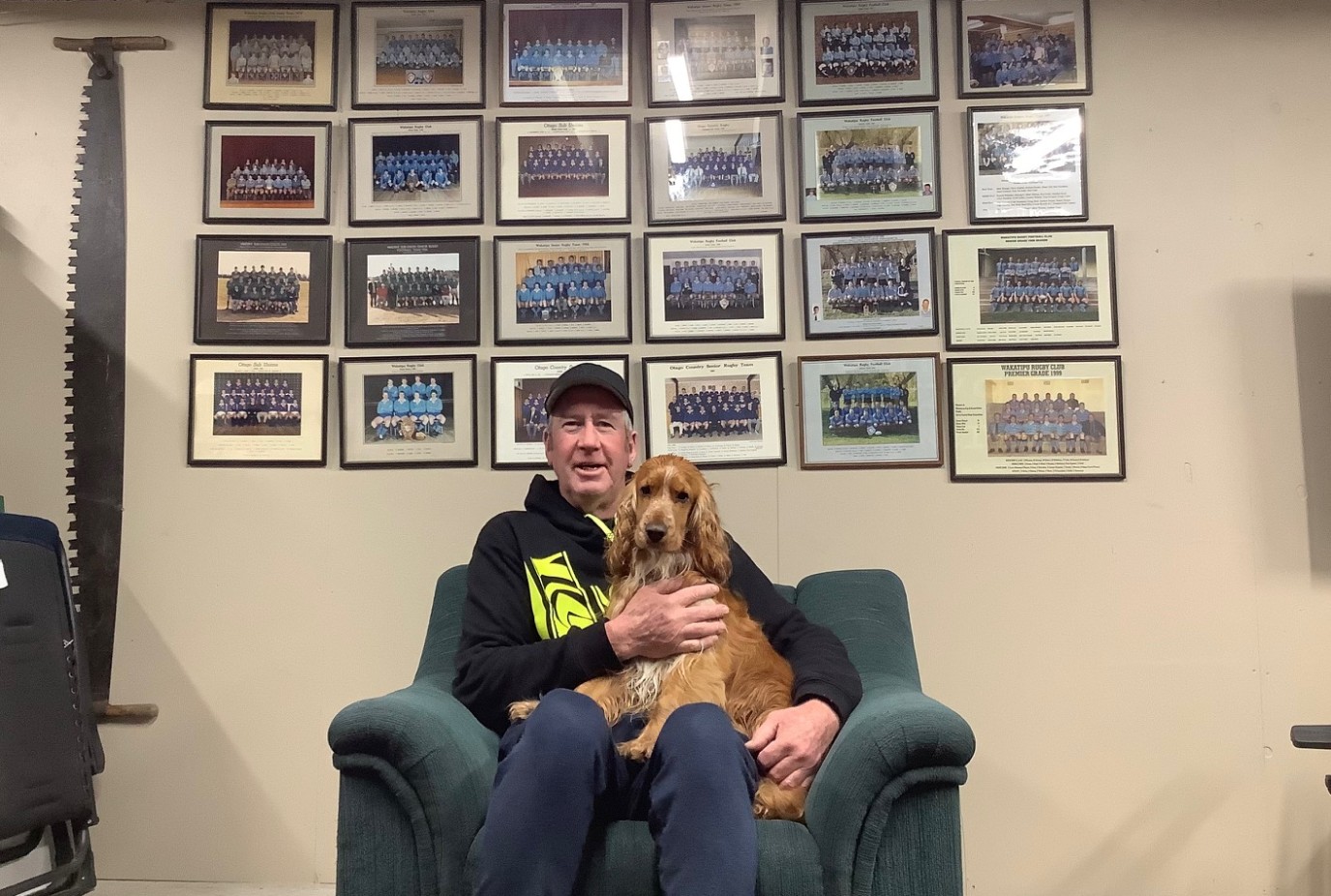 Steve with their Cocker Spaniel Mani in front of 20 years of Wakatipu and Otago Country rugby memorabilia